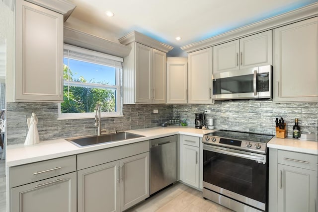 kitchen with tasteful backsplash, appliances with stainless steel finishes, sink, and gray cabinetry