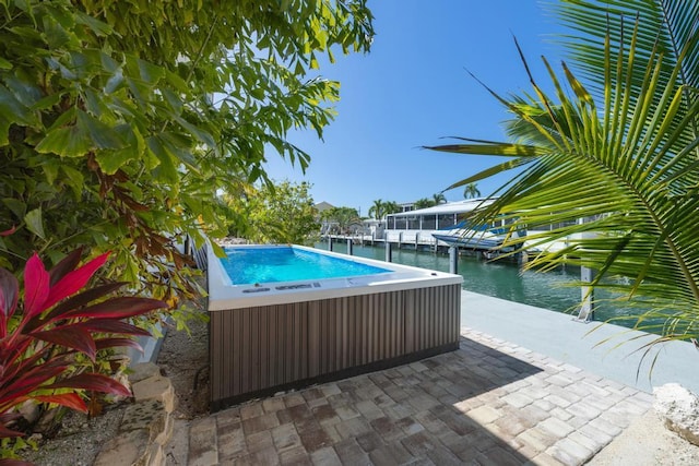 view of swimming pool with a dock, a hot tub, and a water view