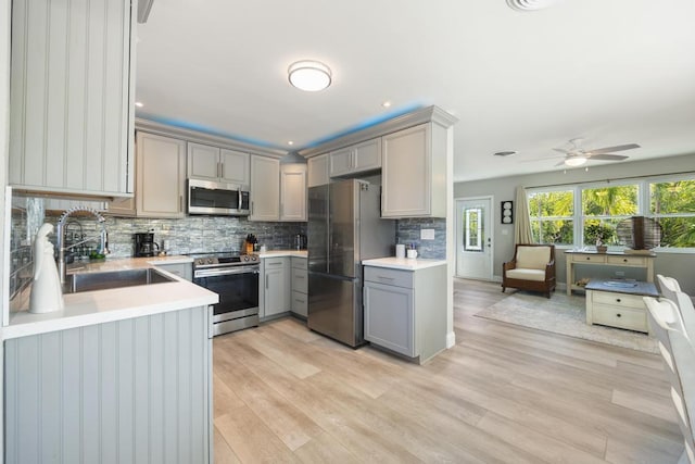 kitchen with tasteful backsplash, appliances with stainless steel finishes, sink, and gray cabinetry