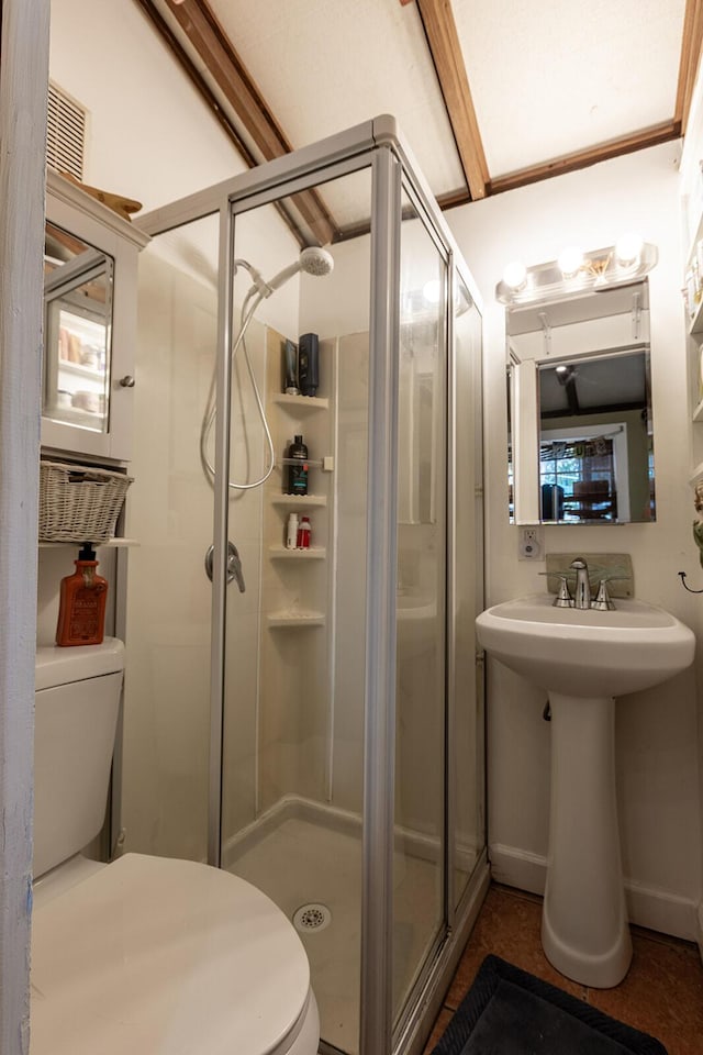 bathroom featuring a shower with door and toilet