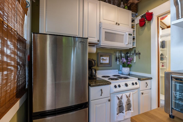 kitchen featuring white cabinetry, dark stone countertops, and white appliances