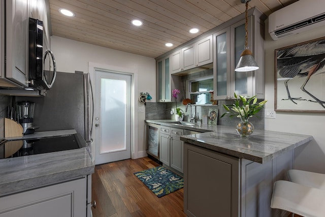 kitchen with a breakfast bar, hanging light fixtures, an AC wall unit, gray cabinets, and kitchen peninsula