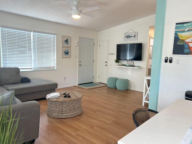 living room with ceiling fan, wood-type flooring, and a textured ceiling