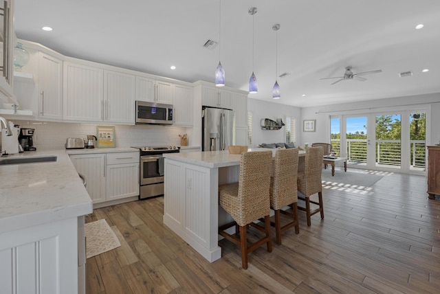 kitchen featuring sink, white cabinetry, decorative light fixtures, a center island, and stainless steel appliances