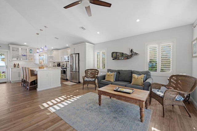 living room with ceiling fan, lofted ceiling, a wealth of natural light, and light hardwood / wood-style floors