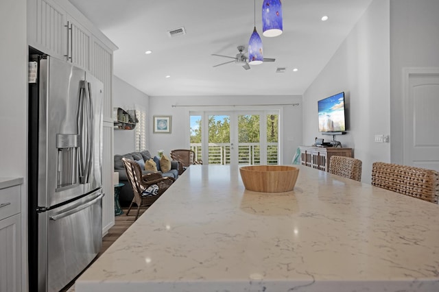 kitchen with stainless steel refrigerator with ice dispenser, white cabinetry, light stone countertops, and french doors