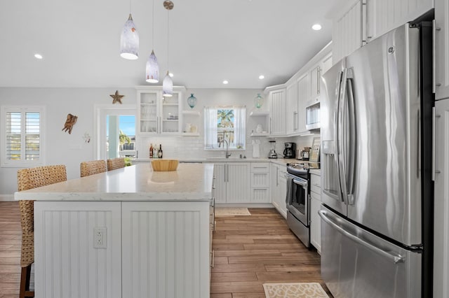 kitchen with decorative light fixtures, white cabinetry, a breakfast bar area, a center island, and stainless steel appliances