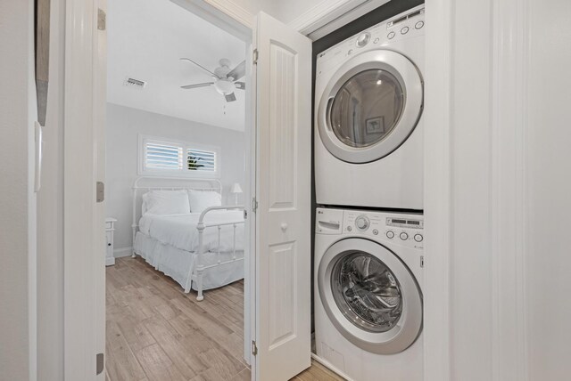 washroom featuring ceiling fan, stacked washer / drying machine, and light hardwood / wood-style floors