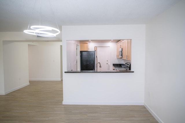 kitchen featuring sink, stainless steel appliances, light hardwood / wood-style floors, light brown cabinetry, and decorative light fixtures