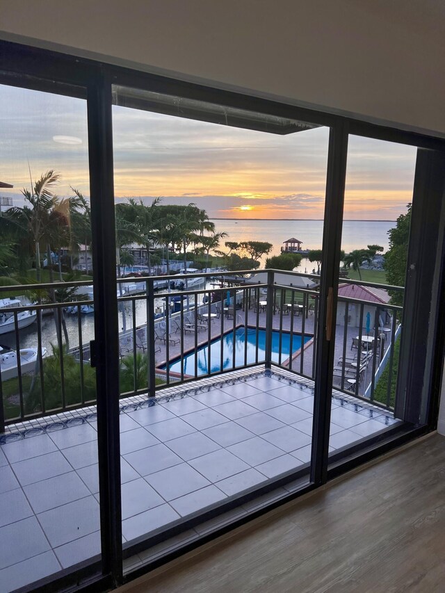 balcony at dusk featuring a water view