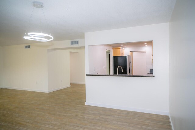 unfurnished living room featuring sink and light hardwood / wood-style flooring