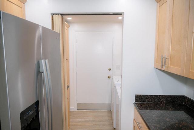 kitchen featuring dark stone counters, light brown cabinetry, stainless steel fridge with ice dispenser, and light hardwood / wood-style flooring