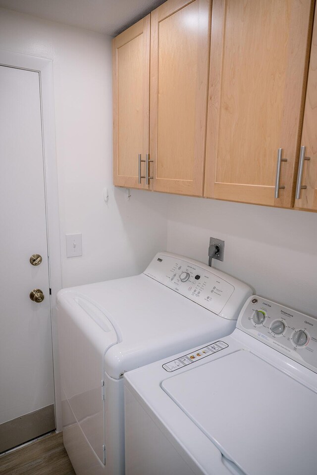 laundry area with dark hardwood / wood-style flooring, washing machine and dryer, and cabinets