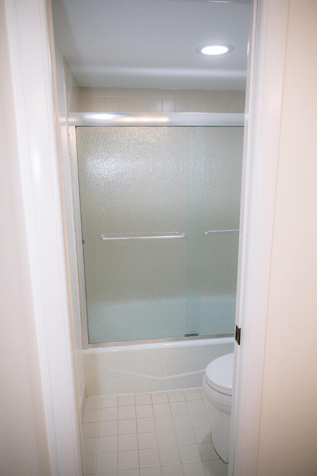 bathroom featuring shower / bath combination with glass door, tile patterned floors, and toilet