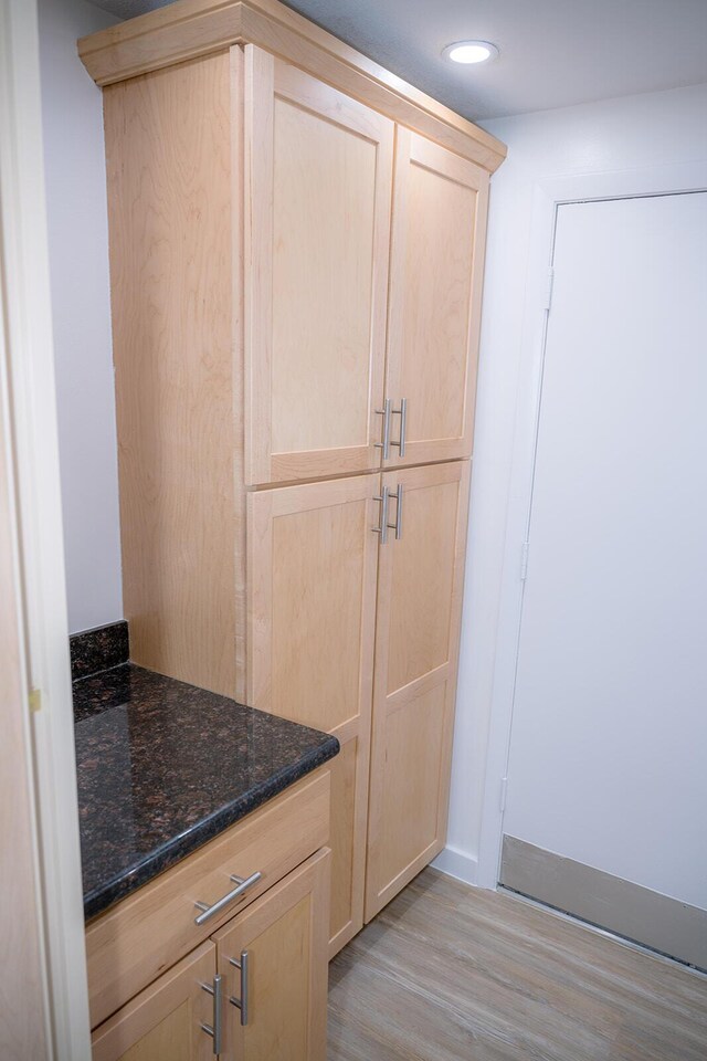 interior space featuring dark stone countertops, light brown cabinets, and light hardwood / wood-style flooring