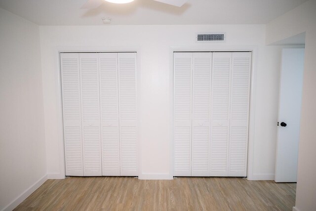 unfurnished bedroom with multiple closets, ceiling fan, and light hardwood / wood-style floors