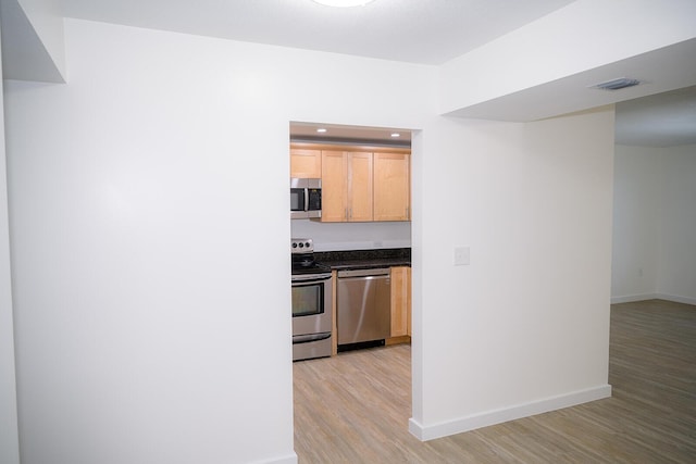 kitchen with appliances with stainless steel finishes, light hardwood / wood-style flooring, and light brown cabinets