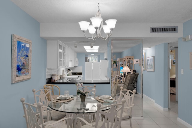 tiled dining room with a chandelier and a textured ceiling