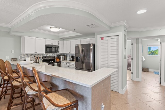 95 Coco Plum Dr Unit 5D, Marathon, FL 33050 - kitchen featuring appliances with stainless steel finishes, a peninsula, light countertops, crown molding, and tasteful backsplash