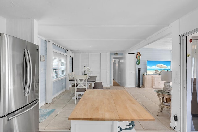 kitchen with butcher block counters, light tile patterned floors, and stainless steel fridge