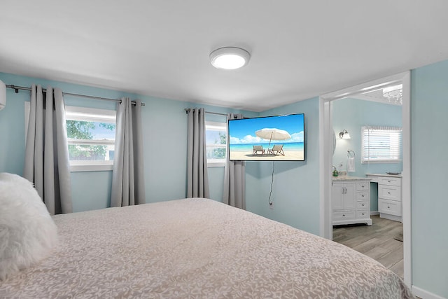 bedroom with connected bathroom and light hardwood / wood-style floors