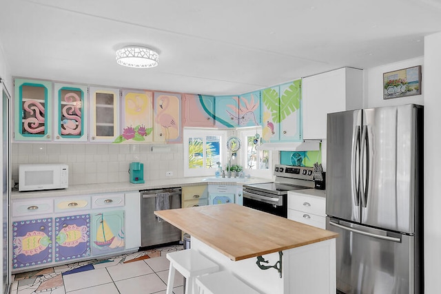 kitchen with white cabinetry, tasteful backsplash, light tile patterned flooring, and appliances with stainless steel finishes