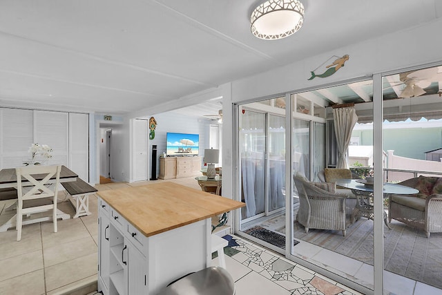 kitchen featuring light tile patterned flooring, butcher block counters, white cabinets, and ceiling fan