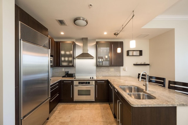 kitchen featuring sink, hanging light fixtures, kitchen peninsula, wall chimney range hood, and black appliances