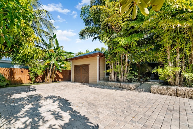 garage featuring decorative driveway and fence