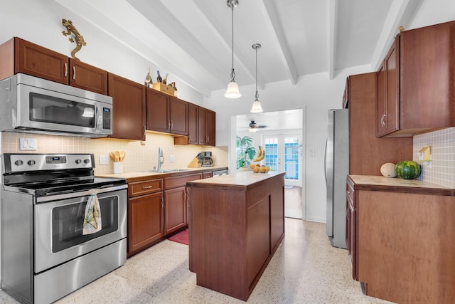 kitchen with a center island, hanging light fixtures, appliances with stainless steel finishes, beamed ceiling, and backsplash