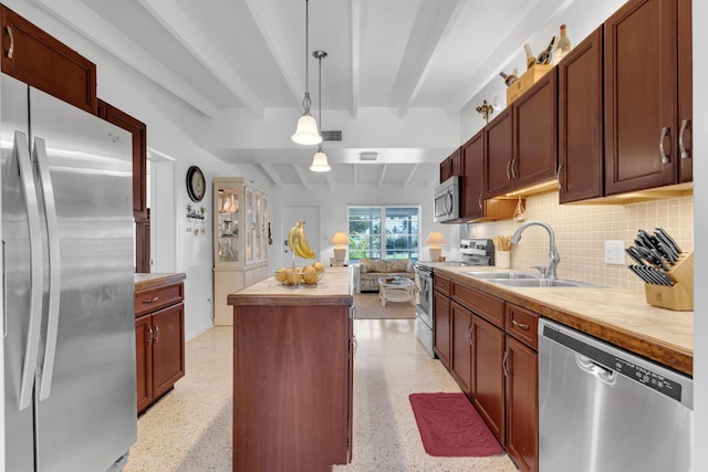 kitchen featuring a kitchen island, pendant lighting, beamed ceiling, sink, and stainless steel appliances