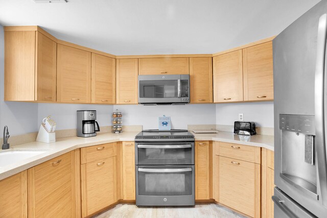 kitchen featuring appliances with stainless steel finishes, sink, and light brown cabinets