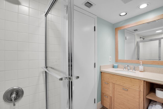 bathroom with tiled shower and vanity