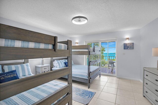 bedroom featuring light tile patterned floors, a textured ceiling, and access to outside