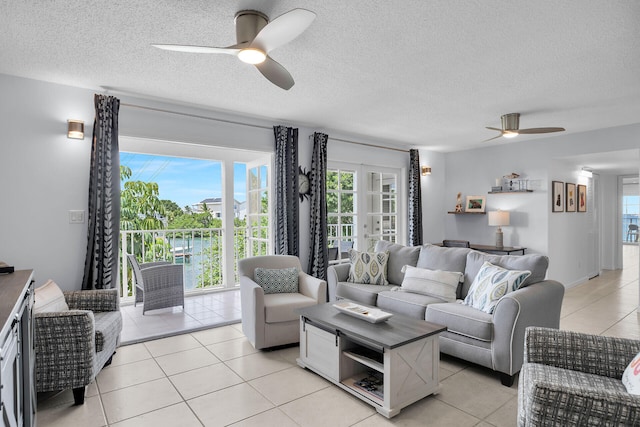 living room featuring light tile patterned floors, a textured ceiling, and ceiling fan