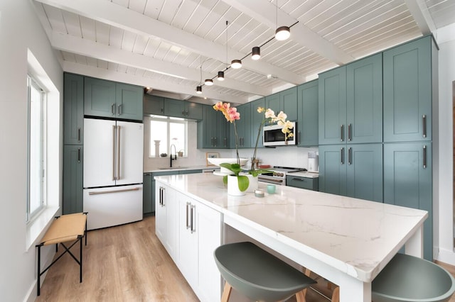 kitchen featuring sink, light hardwood / wood-style flooring, beam ceiling, premium appliances, and light stone countertops