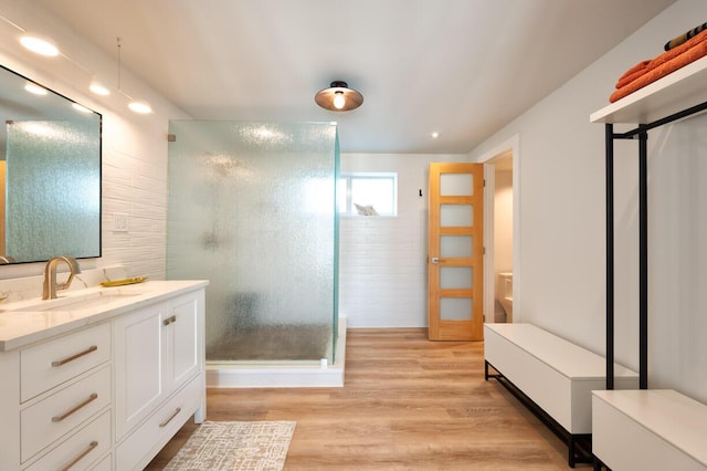 bathroom with an enclosed shower, vanity, and wood-type flooring