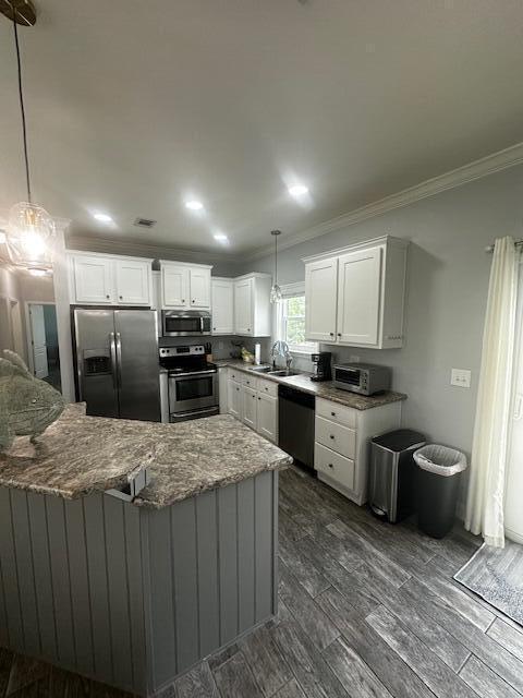 kitchen with sink, crown molding, white cabinetry, stainless steel appliances, and decorative light fixtures