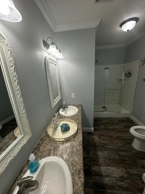 bathroom with a tile shower, vanity, crown molding, and toilet