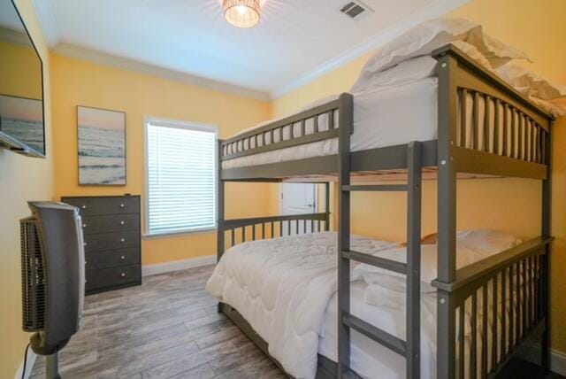 bedroom with ornamental molding and hardwood / wood-style floors