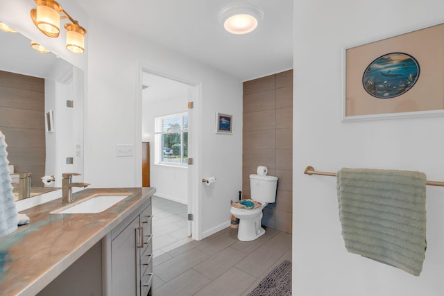 bathroom with vanity, tile walls, and toilet