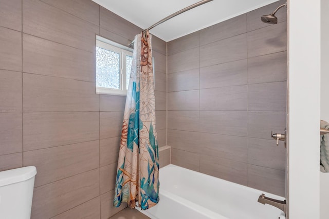 bathroom featuring toilet, shower / tub combo, and tile walls