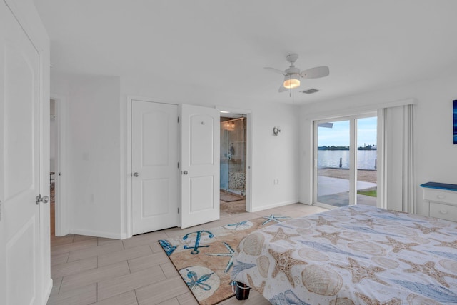 bedroom with access to exterior, ensuite bathroom, ceiling fan, and a water view