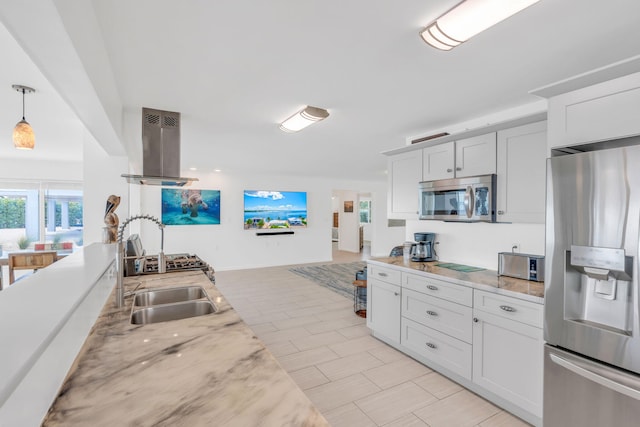 kitchen featuring pendant lighting, white cabinetry, stainless steel appliances, island range hood, and light stone countertops