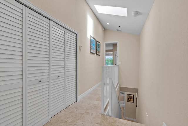 hall featuring vaulted ceiling with skylight