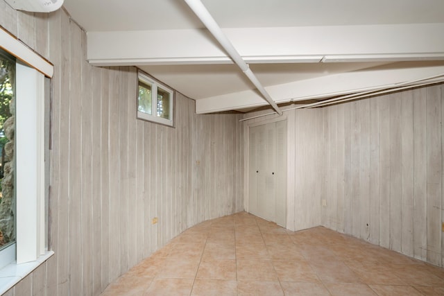below grade area with tile patterned flooring and wooden walls