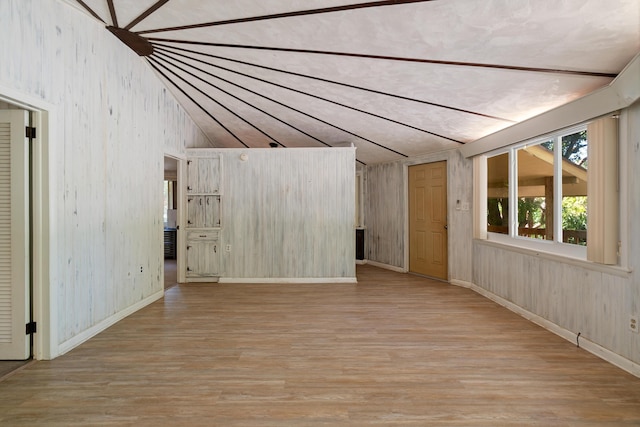 unfurnished room with vaulted ceiling, wood finished floors, and baseboards