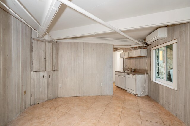interior space with light tile patterned floors, wooden walls, a wall mounted AC, and a sink