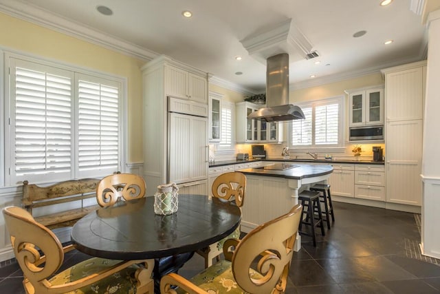 kitchen featuring dark countertops, glass insert cabinets, white cabinets, island range hood, and built in appliances