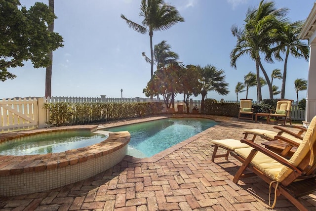 view of swimming pool featuring a patio area, a fenced backyard, and a pool with connected hot tub